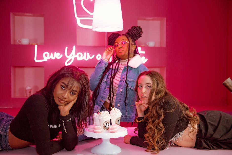 Three fashionable teenagers enjoy a vibrant party setting with desserts and neon lights.
